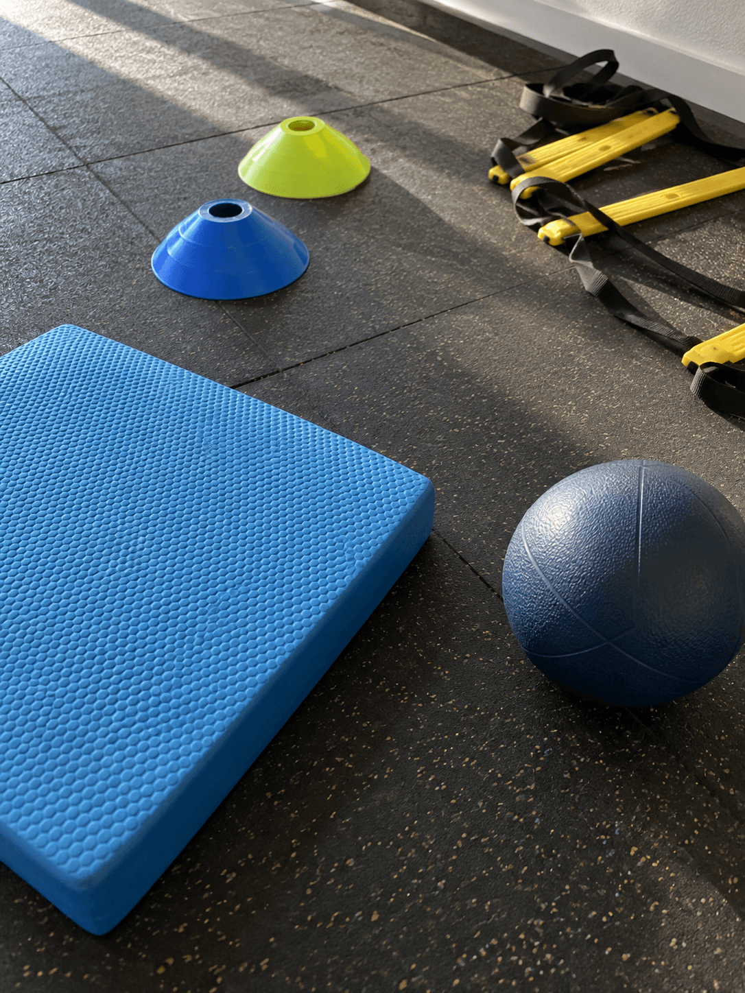 Balance-Pad, Hütchen, Medizinball und Koordinationsleiter auf dem Trainingsboden