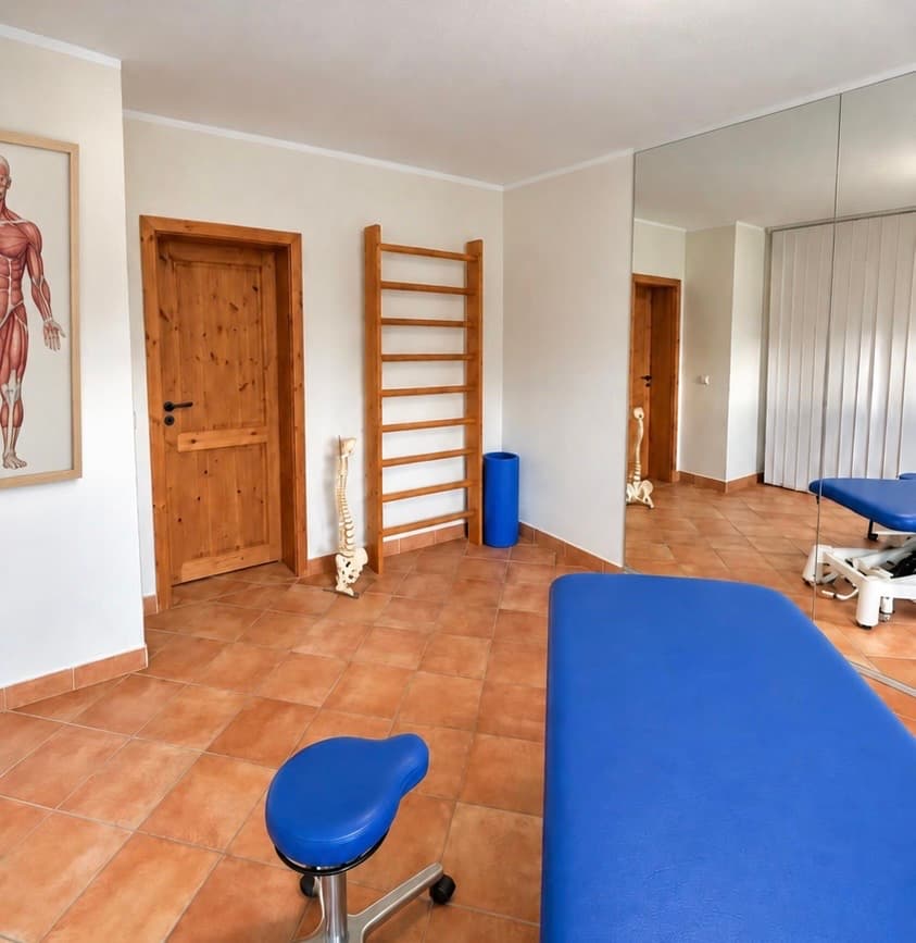 Behandlungsraum mit Therapieliege, Sprossenwand und Anatomietafel